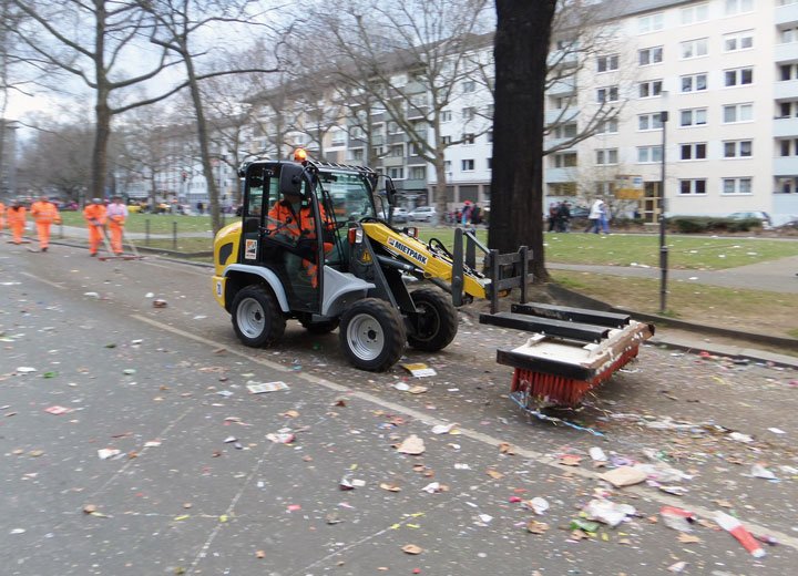 Mit Besen ausgestattet schoben Radlader von HKL die Überreste des Karnevalsumzuges von den Straßenrändern in die Mitte der Fahrbahn